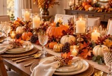 Elegant Thanksgiving table with pumpkins, fall leaves, candles, cream dinnerware, and gold accents